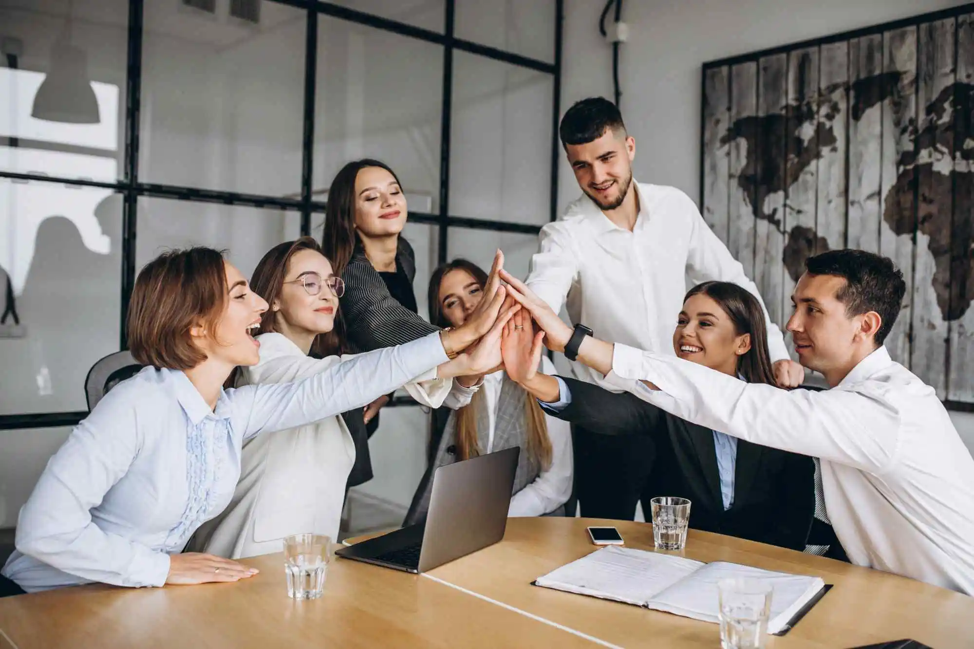 Colleagues joining hands above a meeting table