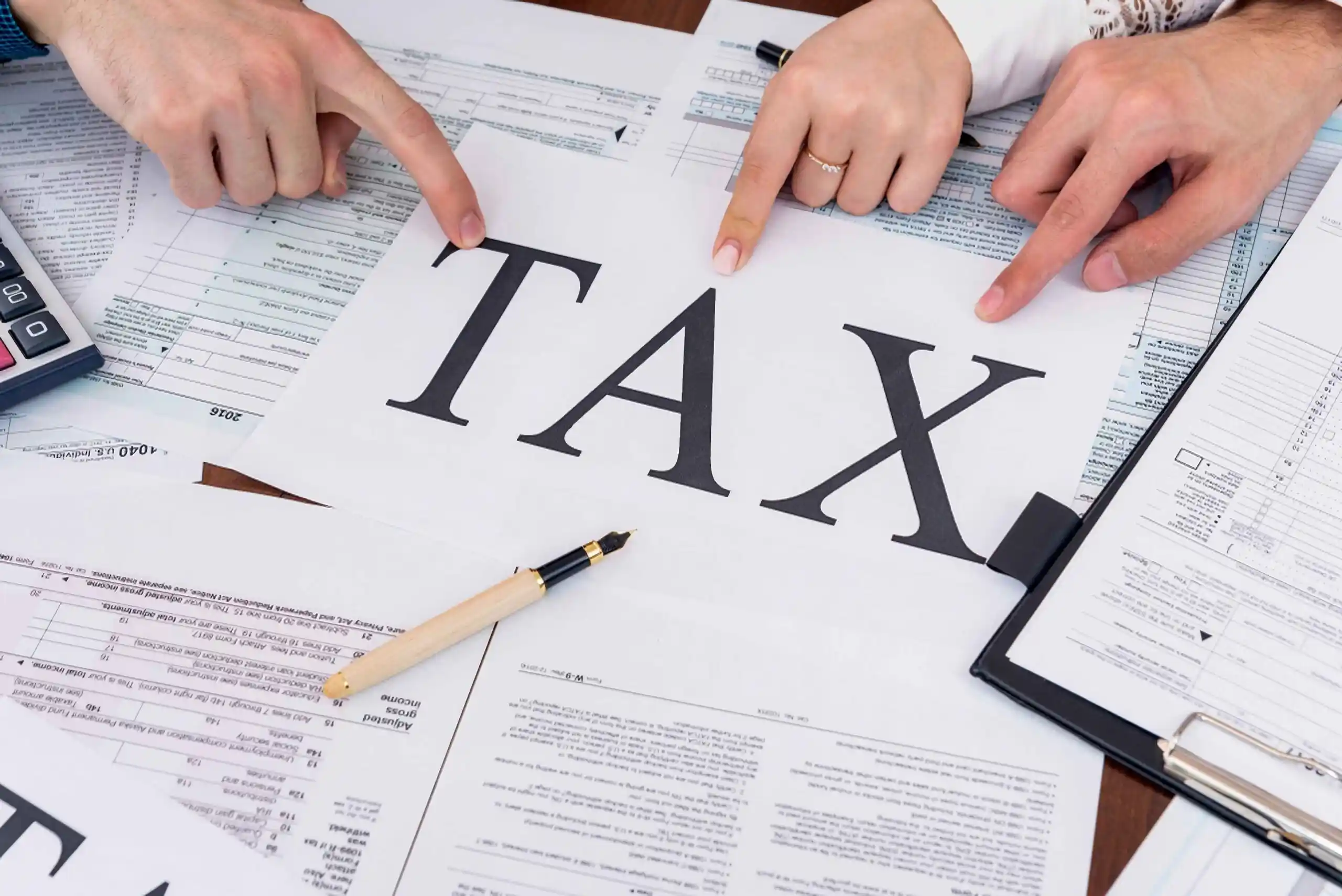 Hands pointing to tax documents and a sheet marked TAX