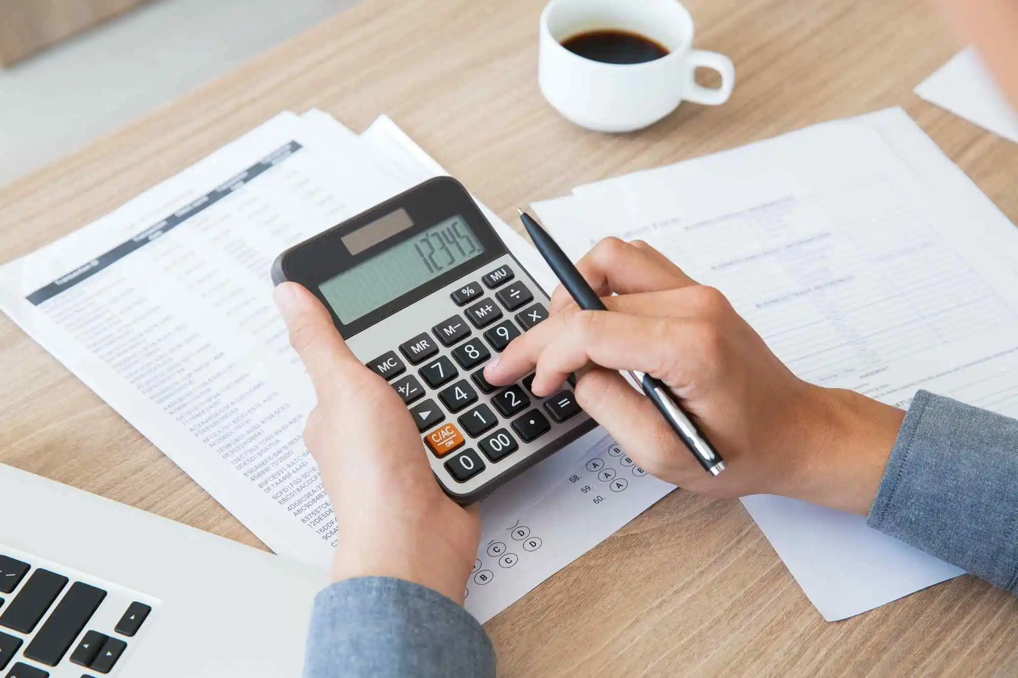 Person using a calculator while reviewing financial documents