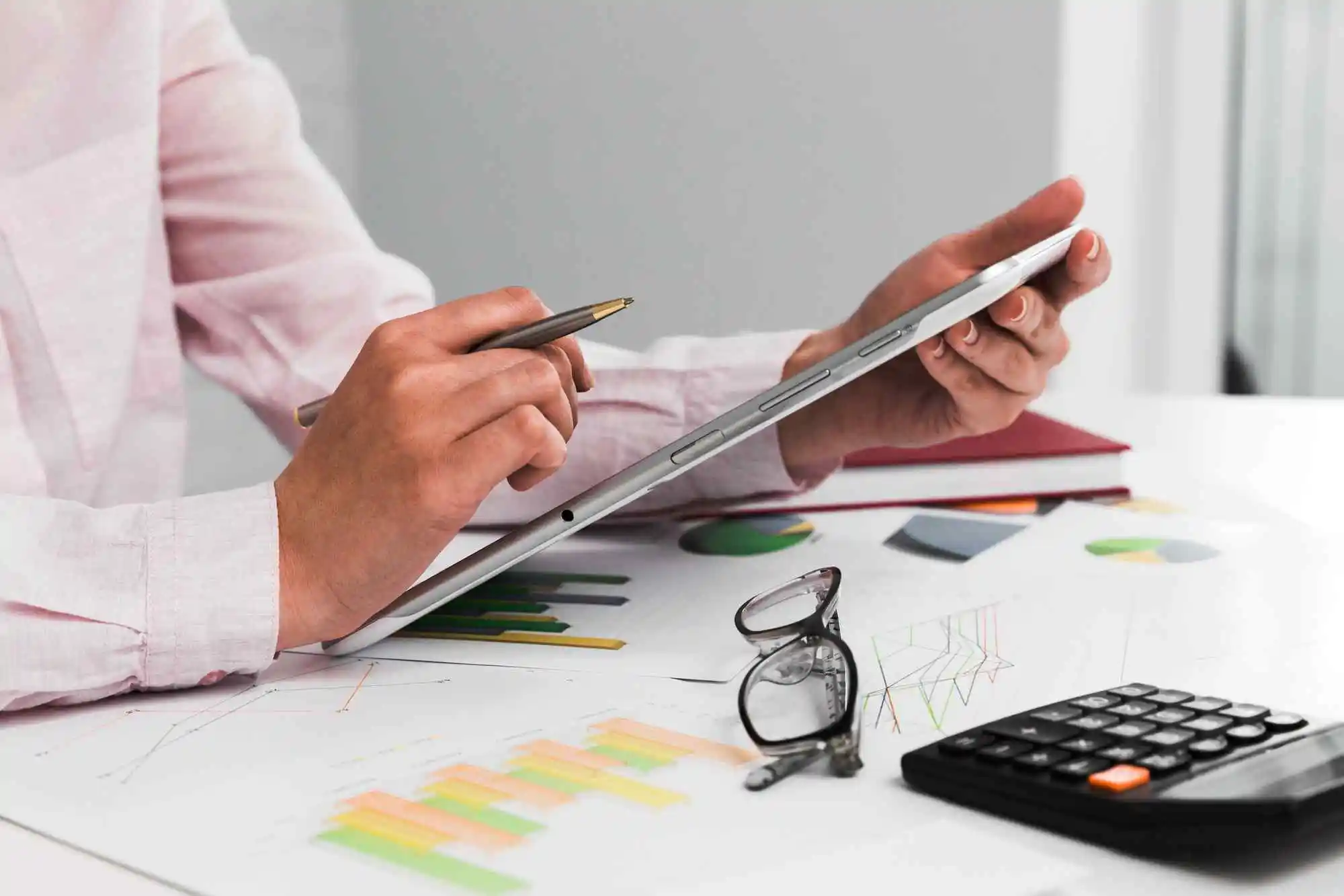 Person reviewing financial charts on a tablet beside a calculator