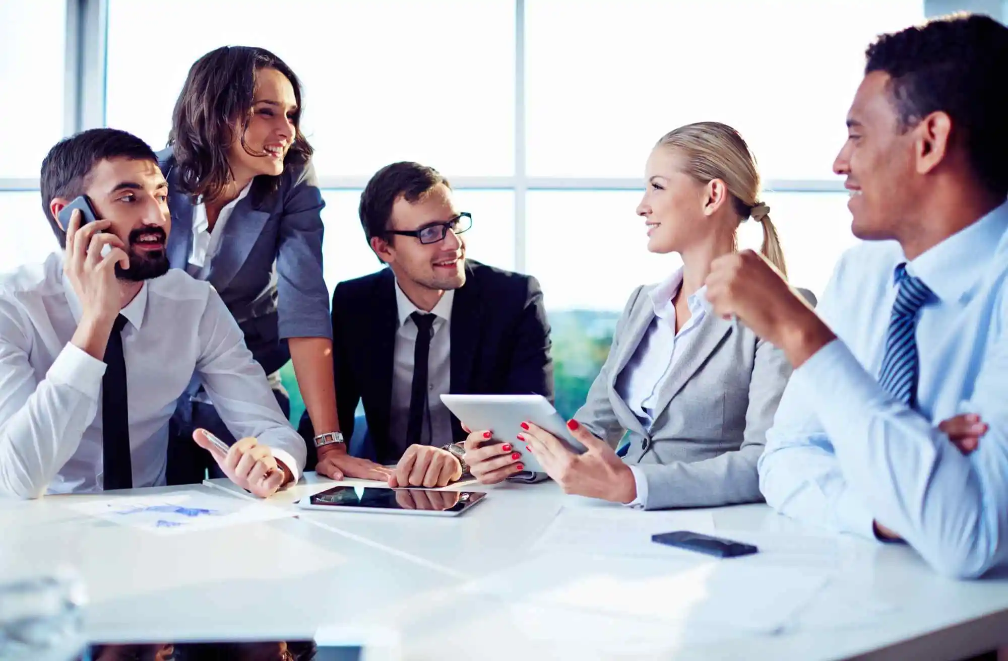 Colleagues discussing work with a tablet and documents at an office table